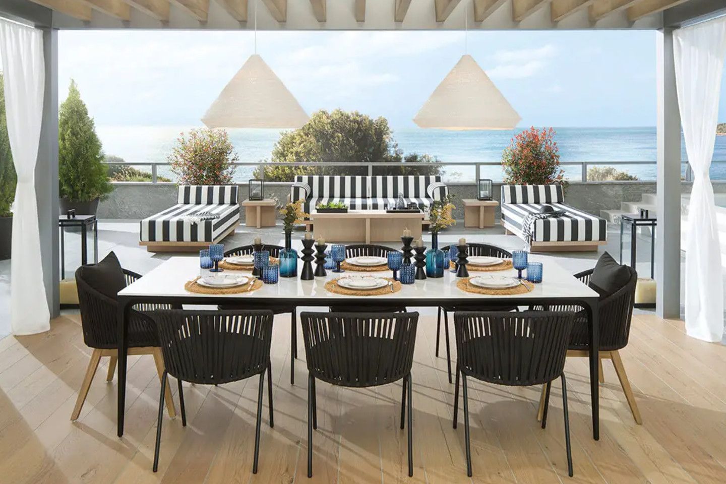 Covered terrace with a dining table and loungers, looking out to the sea