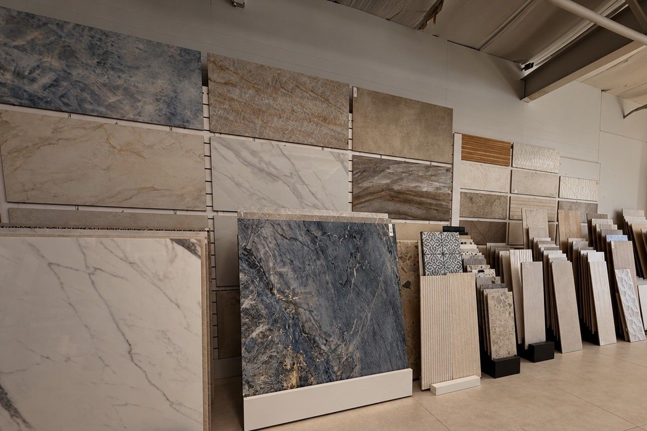 Marble-look porcelain slabs on a wall of our showroom, with tile samples on racks below