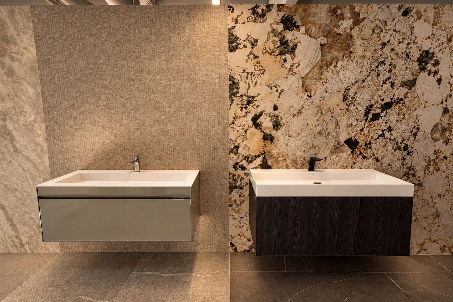 Two floating vanities in front of a textured tile wall and a granite-look slab wall in our showroom