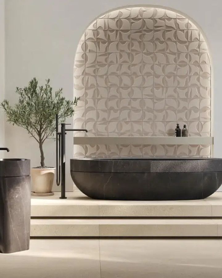 Dark stone bathtub in front of an arched wall of patterned relief tile